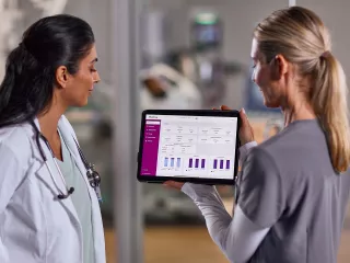 Two female healthcare professionals look at data on an tablet